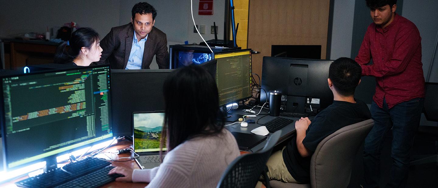 Five people in a dark computer lab